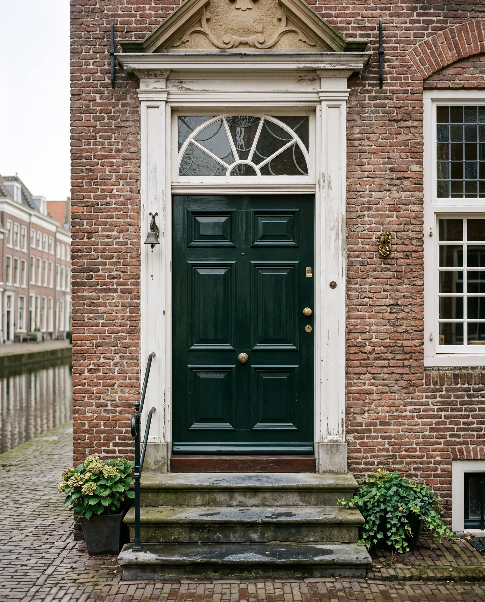 Grachtenpand met diepgroene voordeur, wit kozijn en bovenlicht